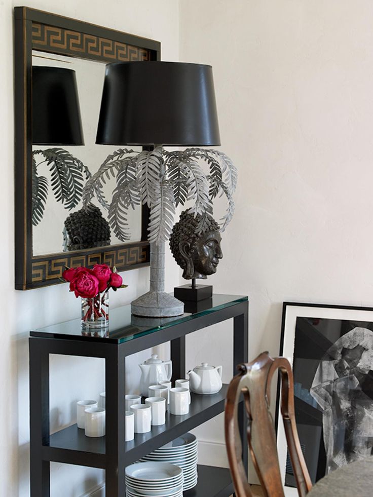 a table with plates and vases on it in front of a wall mounted mirror