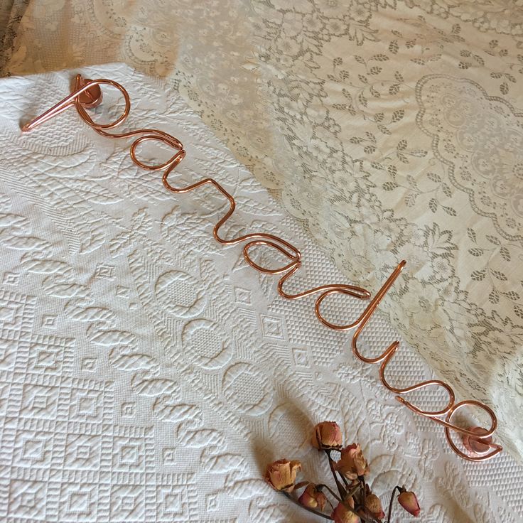 a close up of a table cloth with flowers on it and the word love spelled in copper wire