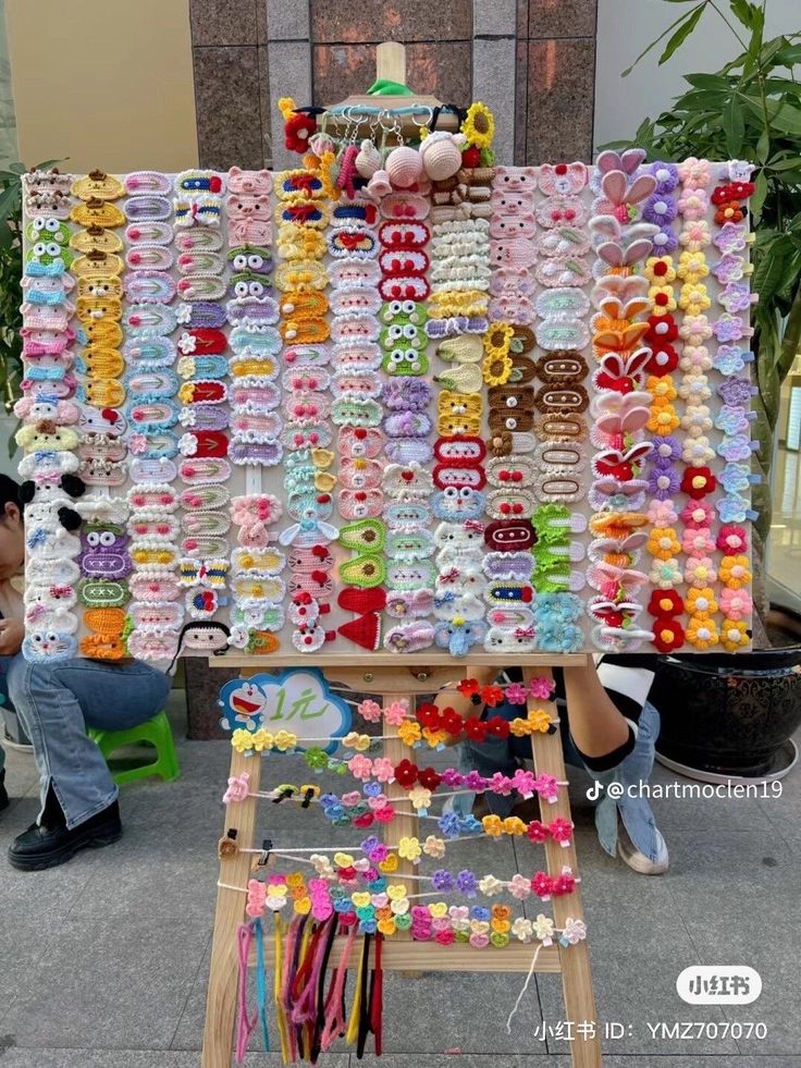 a woman standing in front of a large display of bracelets and hair clips on a easel