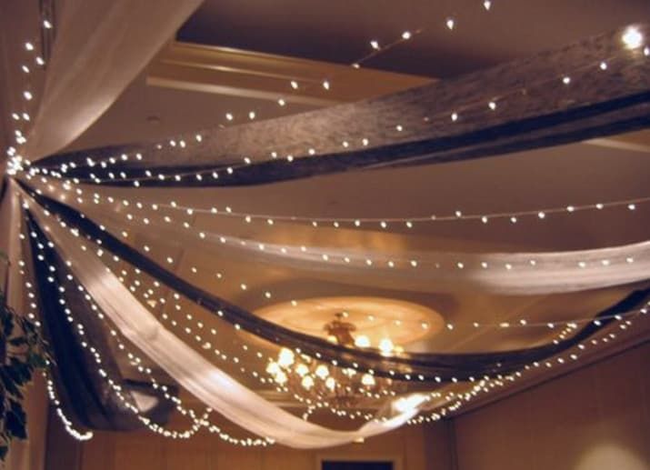 the ceiling is decorated with white lights and draping on it's sides