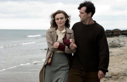 a man and woman walking on the beach together