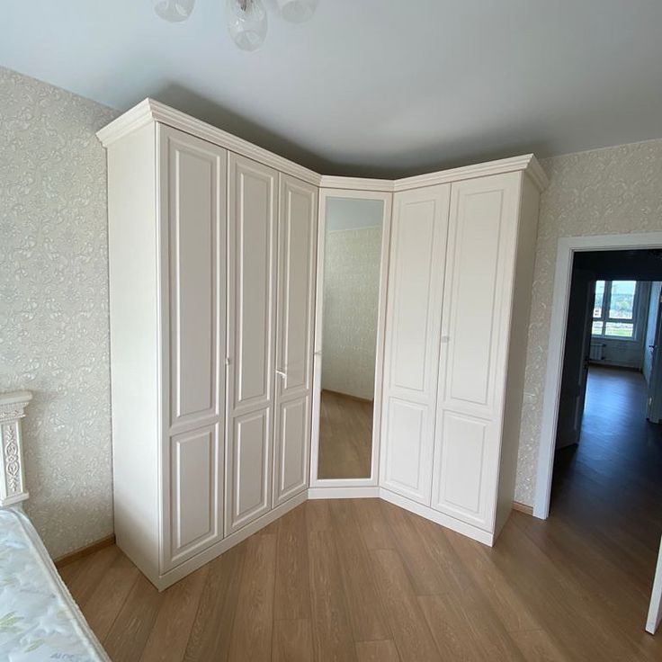 an empty bedroom with white closets and wood floors