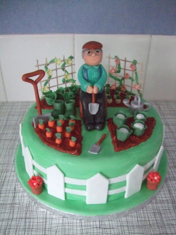 a cake with a man sitting on top of it in the middle of a garden