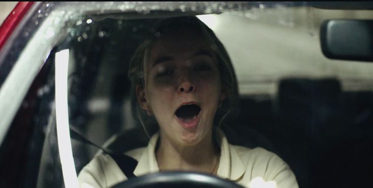 a woman with her mouth open sitting in the passenger seat of a car and screaming