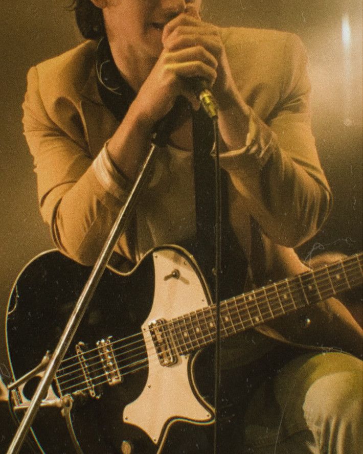 a man holding a guitar while singing into a microphone