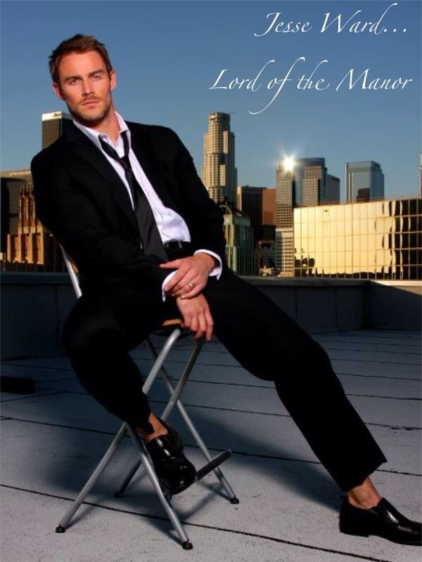 a man in a suit and tie sitting on a chair with the city skyline behind him