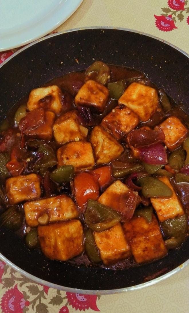 a pan filled with tofu and vegetables on top of a table