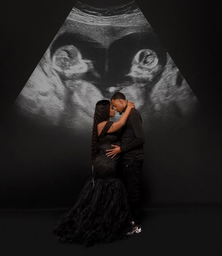 a man and woman embracing in front of a black background