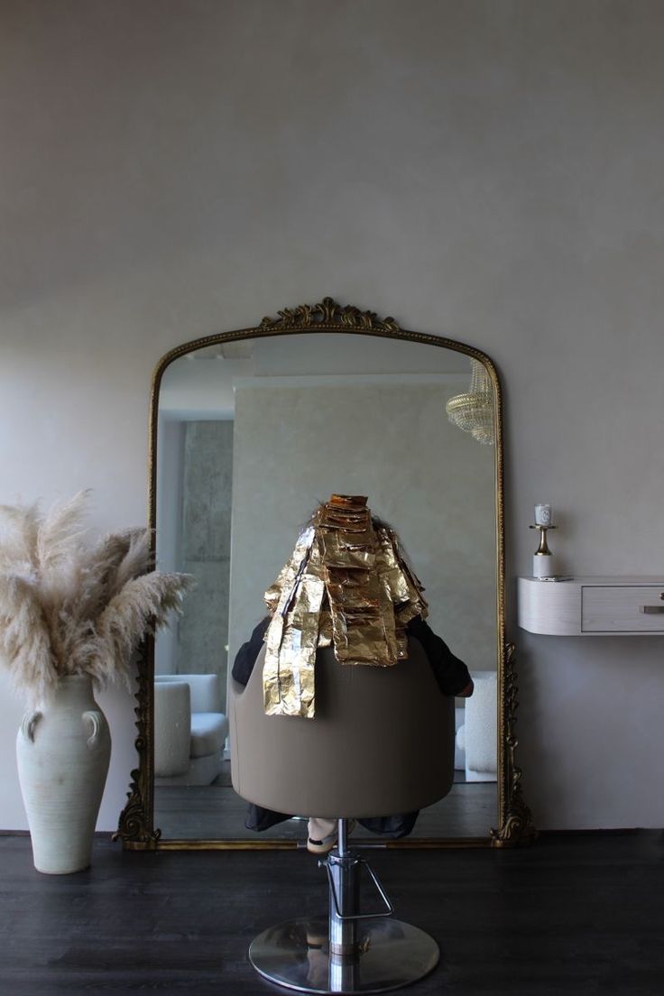 a mirror sitting on top of a table next to a vase