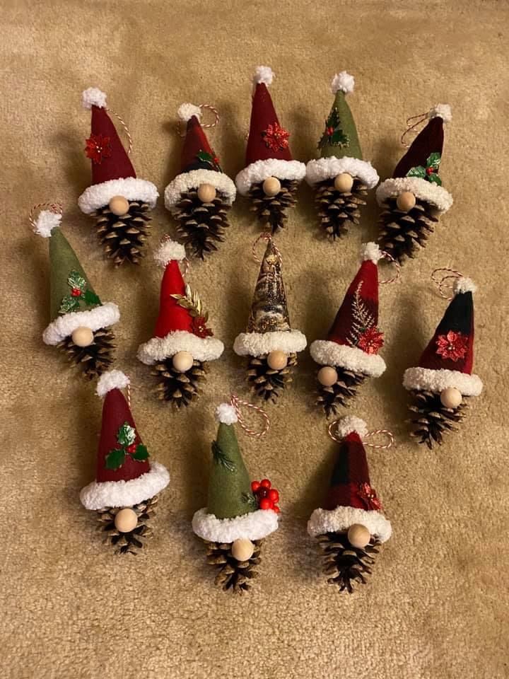 a bunch of pine cones with santa hats on them sitting on the floor next to each other