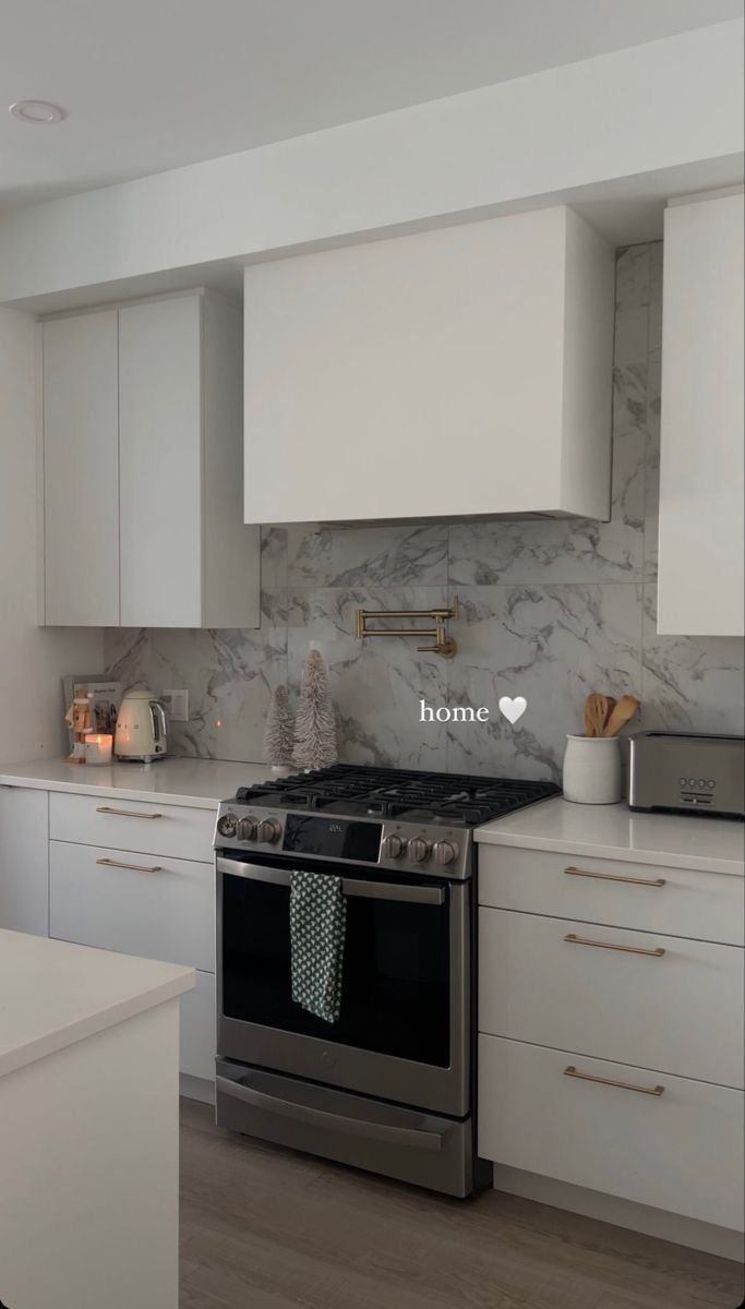 a kitchen with white cabinets and marble backsplash, stainless steel range hoods