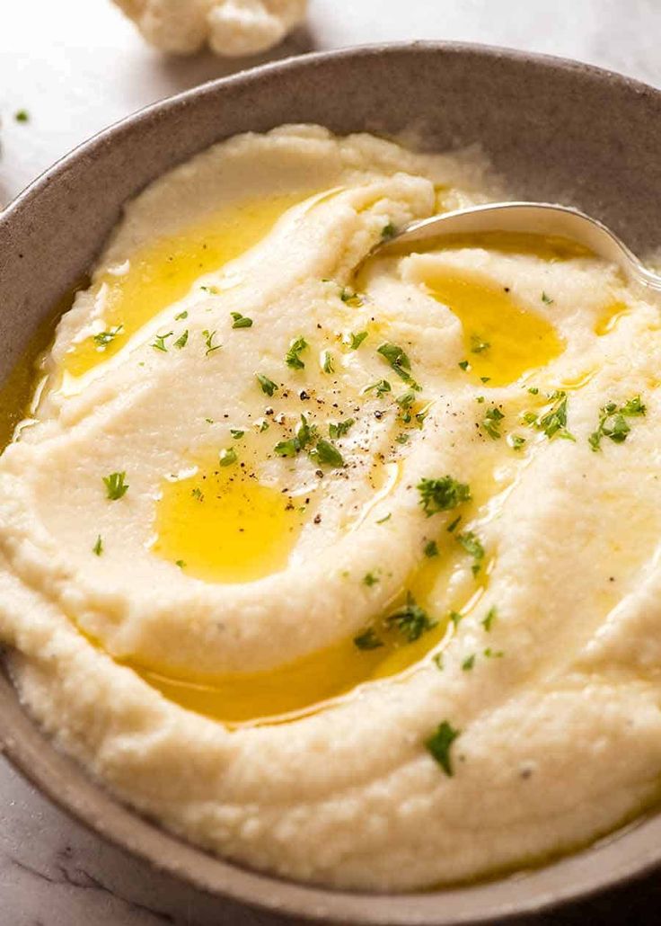 mashed potatoes with olive oil and parsley in a gray bowl on a white tablecloth