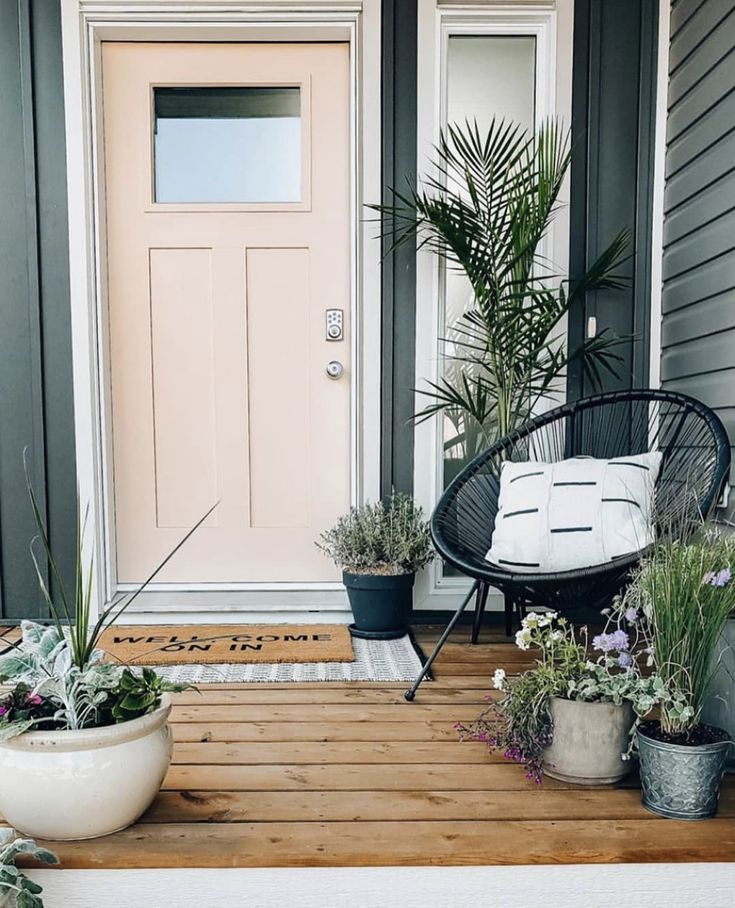 a porch with potted plants and a chair on the front steps next to a door