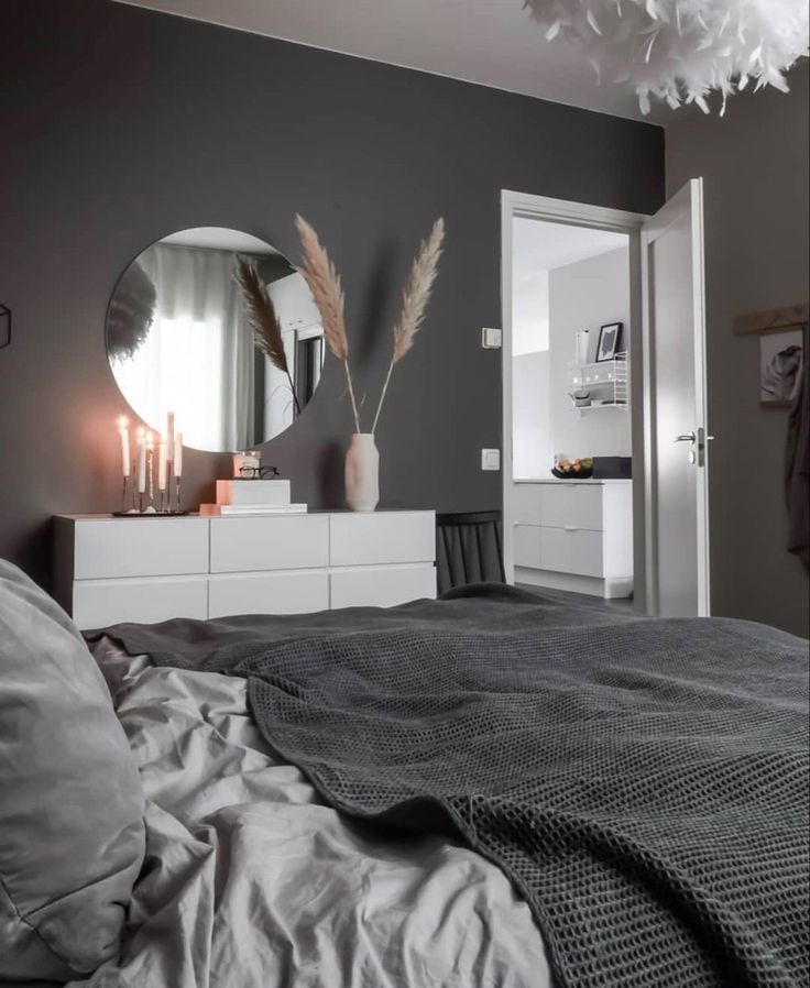 a bedroom with grey walls, white furniture and large feathers hanging from the ceiling over the bed