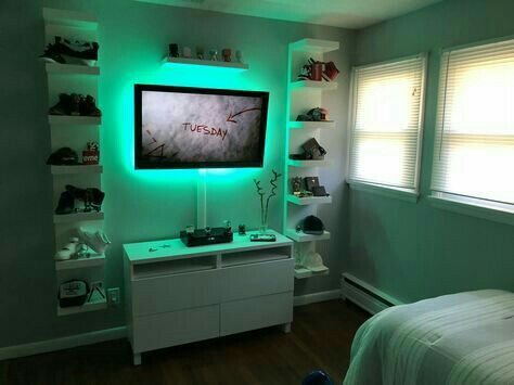 a bedroom with green lights and a flat screen tv mounted on the wall above it