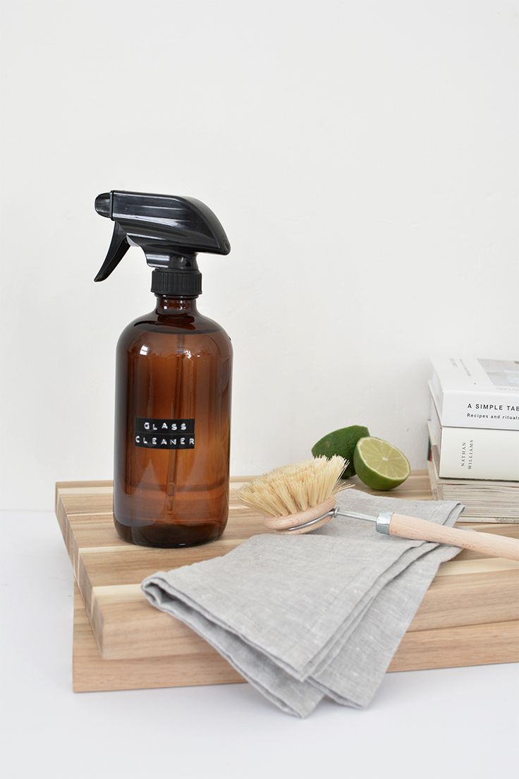 a bottle of cleaner sitting on top of a wooden cutting board next to a cloth