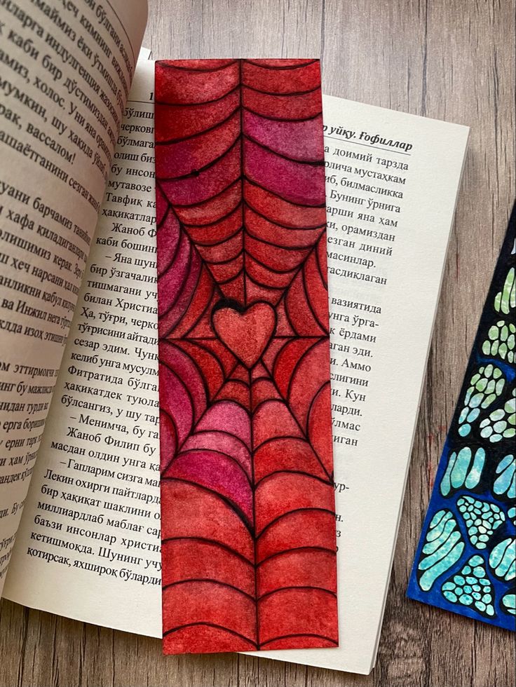 an open book with watercolors on it next to a spiderweave design