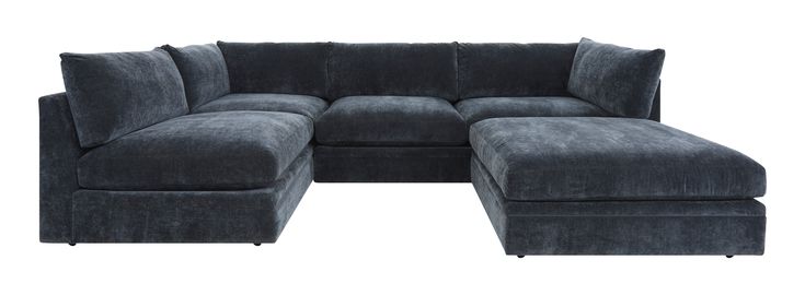 a large gray sectional couch sitting next to a footstool on top of a white floor