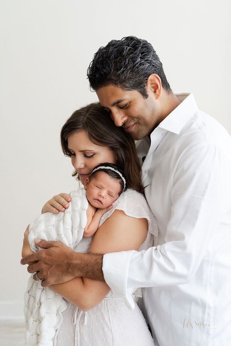 a man and woman holding a baby in their arms