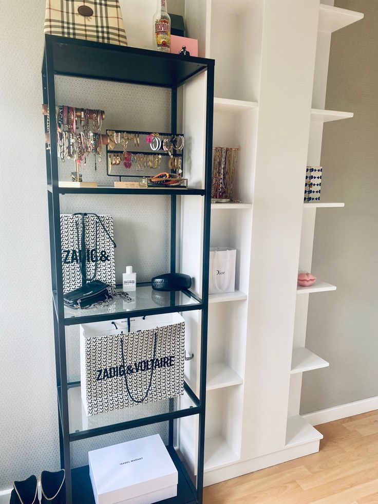 a black and white shelf with bags on it in a living room next to a bookshelf