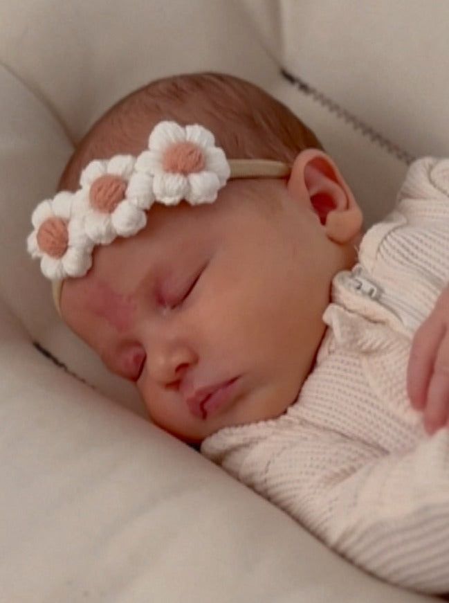 a baby is sleeping in a white crib with flowers on it's head