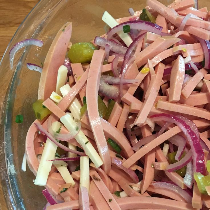 a bowl filled with meat and veggies on top of a wooden table