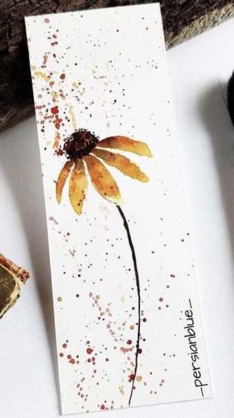 a card with a flower painted on it next to some paintbrushes and an ink pen