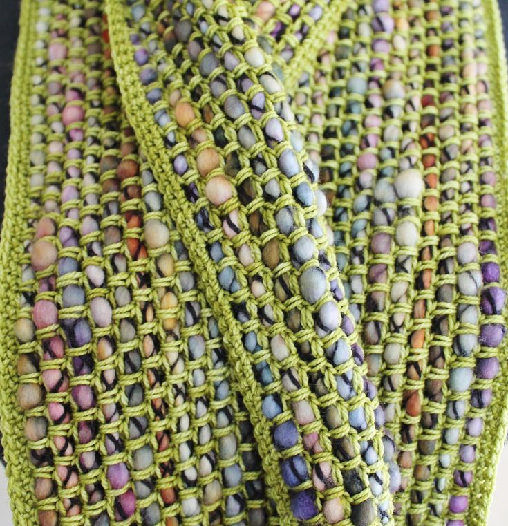 a close up view of a green knitted tie with multicolored beads on it