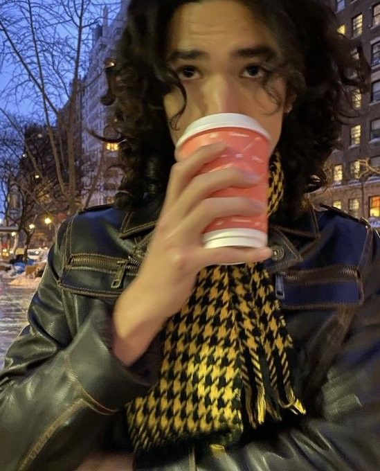 a man with long hair drinking from a cup