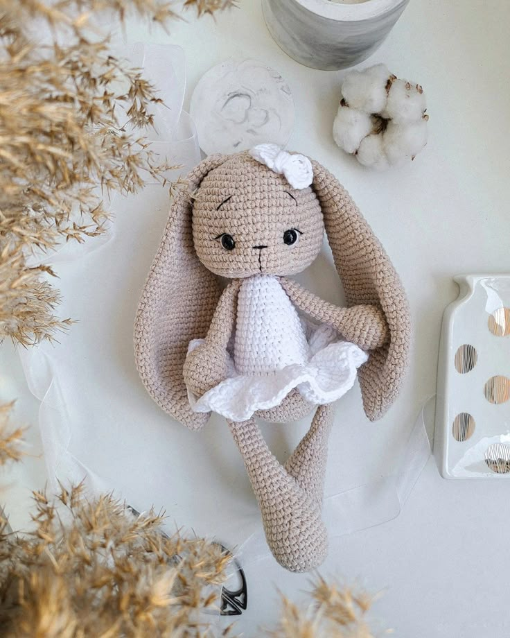 a crocheted stuffed animal sitting on top of a table next to some dried flowers