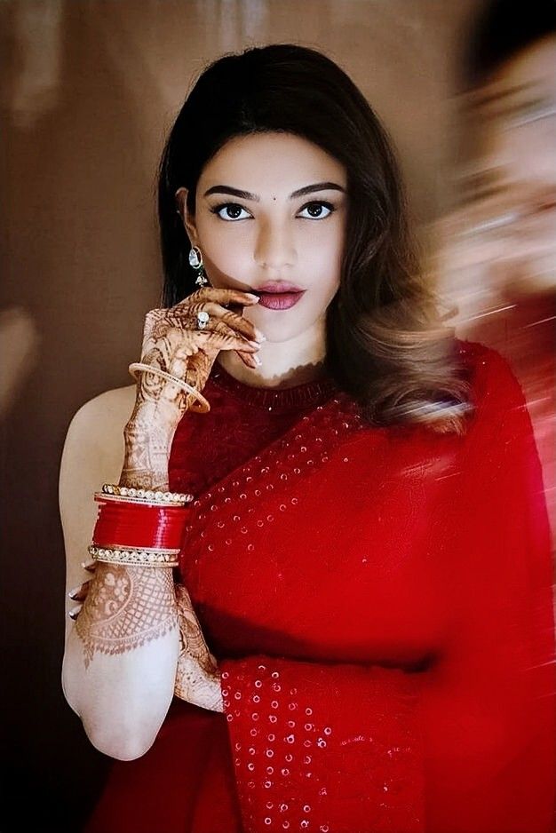 a woman in a red dress holding her hands up to her face and looking at the camera