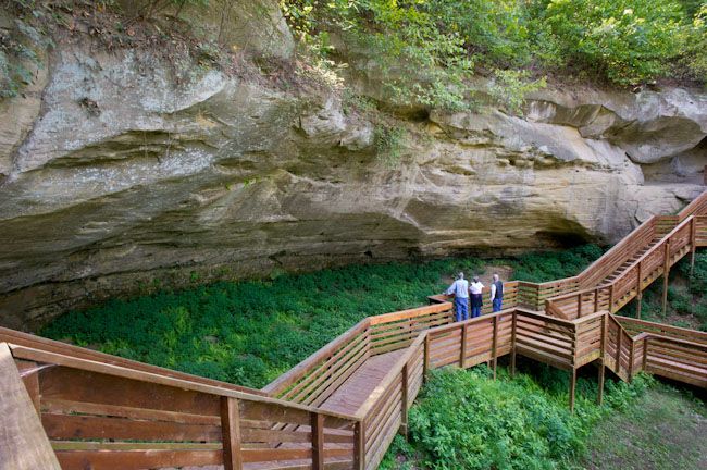 two people are walking up the stairs to a cave