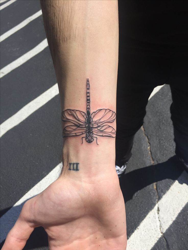 a person with a dragonfly tattoo on their wrist