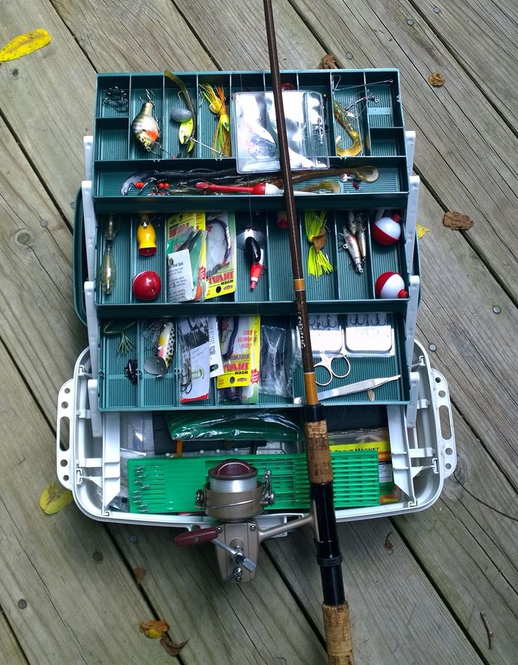 a fishing tackle box filled with lots of different types of fishing gear and accessories on top of a wooden deck