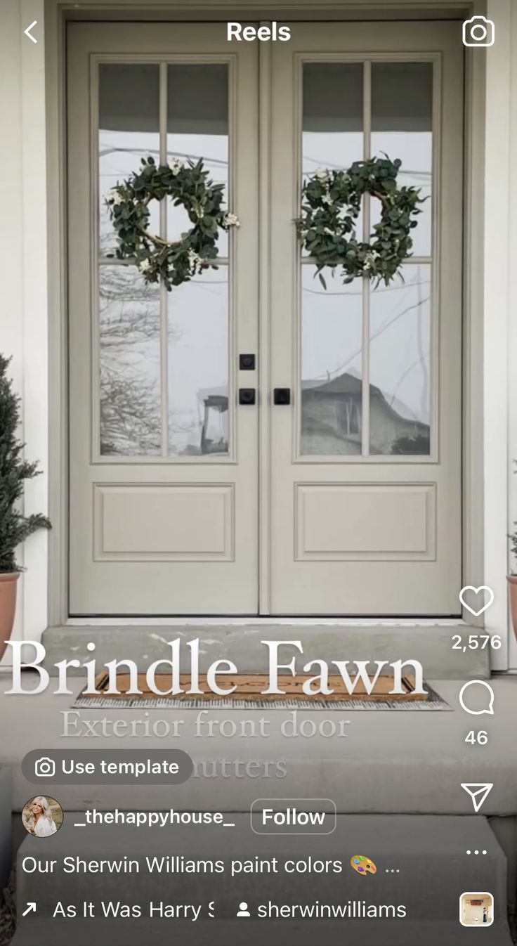 the front door is decorated with wreaths and two potted plants on top of it