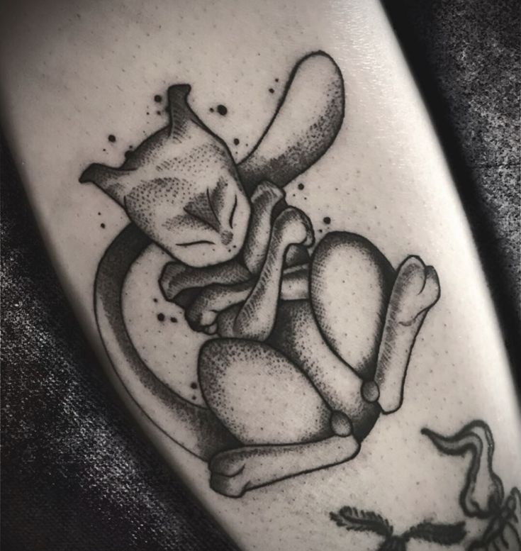 a black and white photo of a cat sleeping on top of a dog bone tattoo