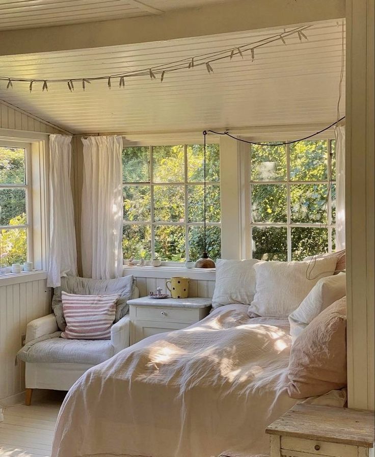 a bed sitting under a window in a bedroom next to a white dresser and chair