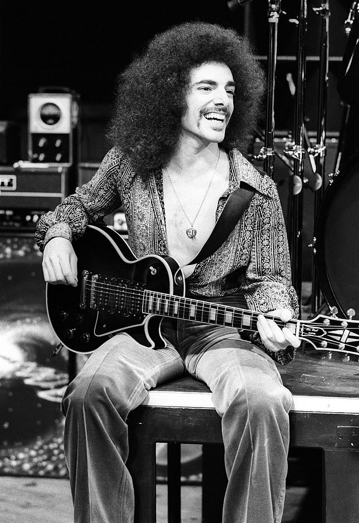 a man sitting on top of a table with an electric guitar in front of him