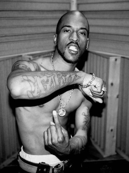 a black and white photo of a man with tattoos on his arm pointing to the side