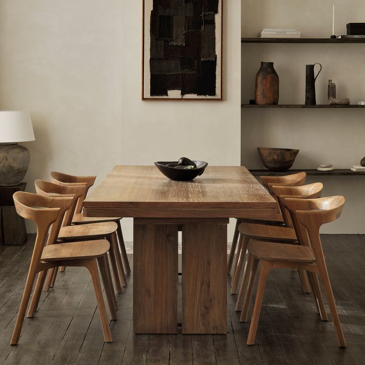 a dining room table with six chairs and a bowl on the top of it in front of shelves