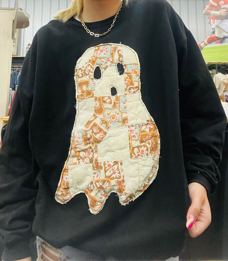 a woman wearing a black sweatshirt with a ghost on it's chest and holding a toothbrush in her hand