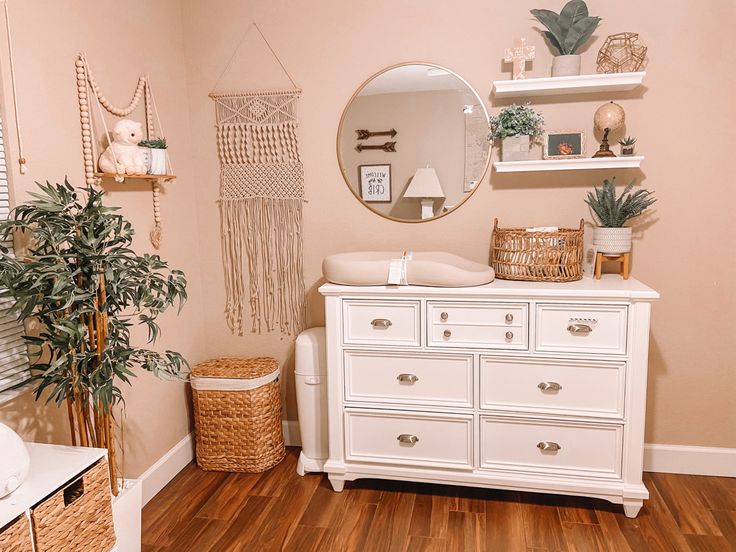 a white dresser sitting next to a mirror on top of a wooden floor in a room