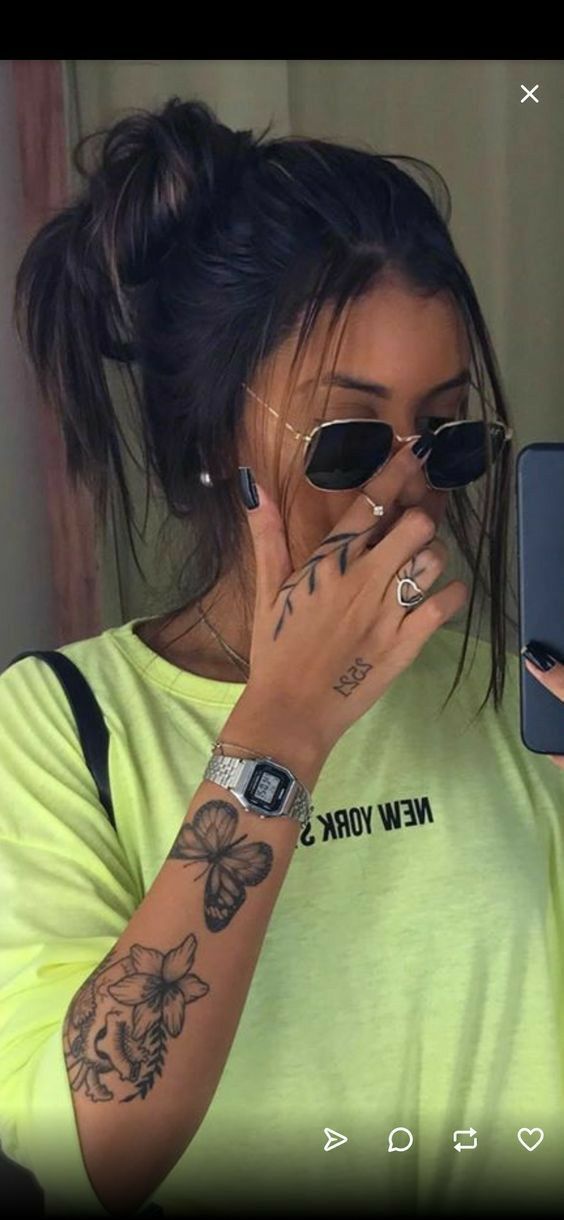 a woman with tattoos on her arm holding a cell phone to her face and looking at the screen