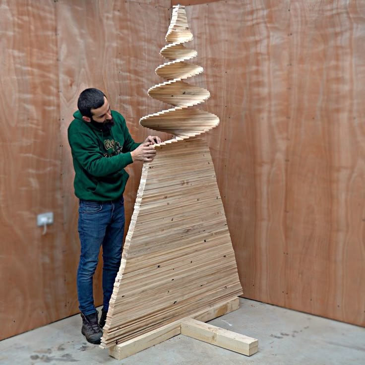 a man standing next to a tall wooden structure made out of plywood planks