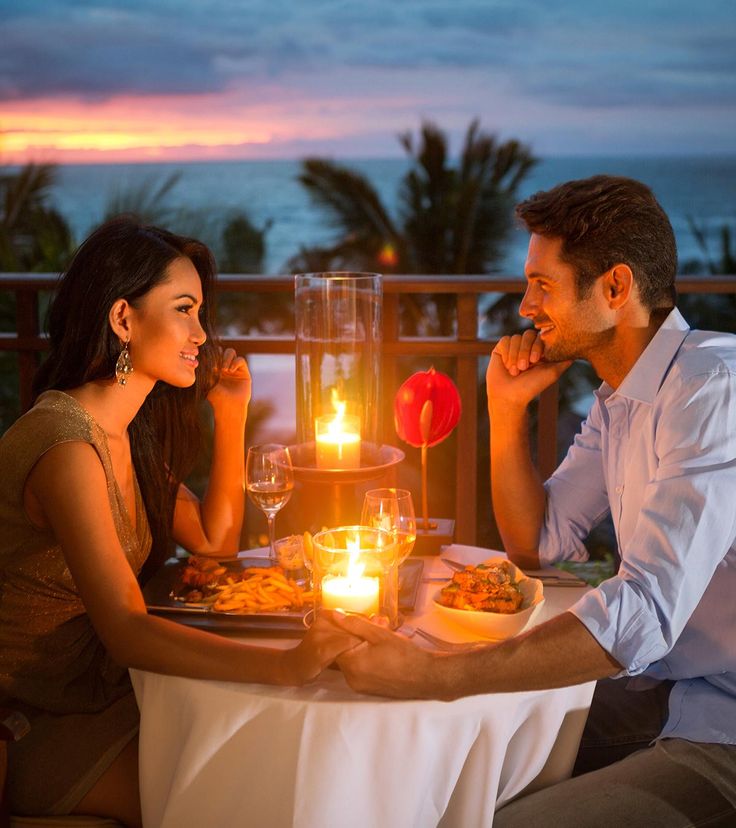 a man and woman sitting at a table with candles in front of them