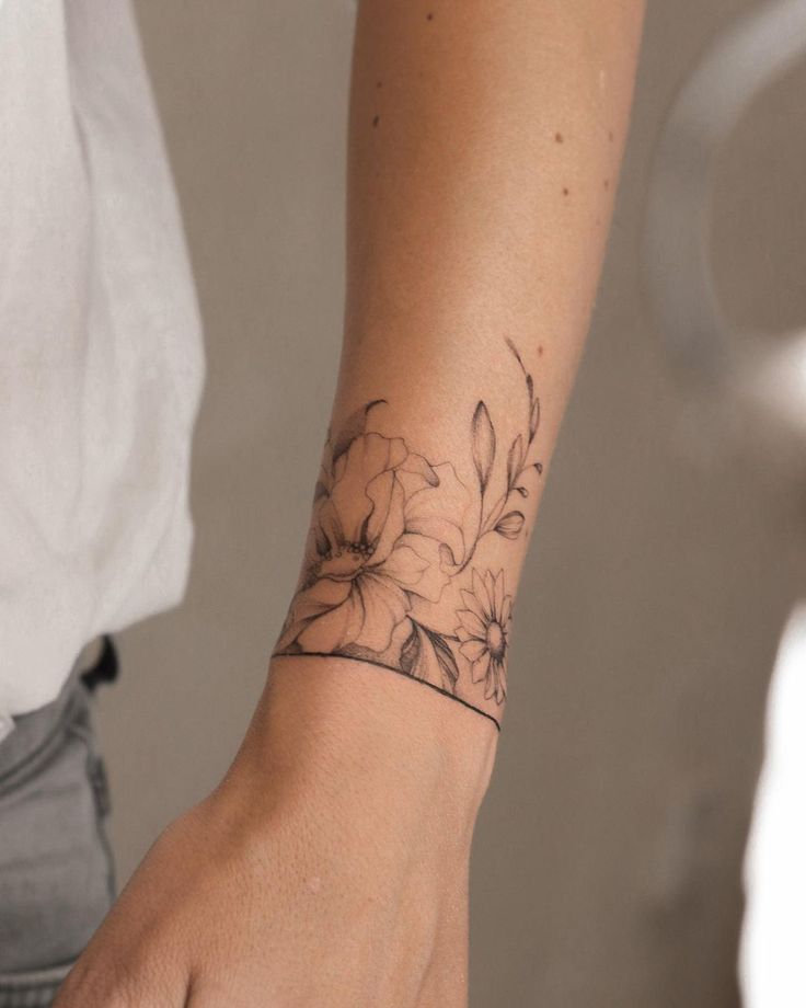 a woman's arm with a flower tattoo on the left side of her wrist