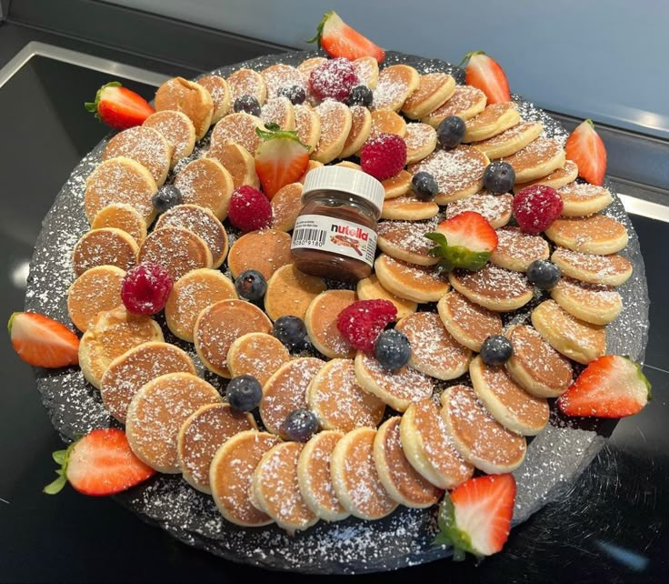 a platter filled with pancakes, strawberries and powdered sugar