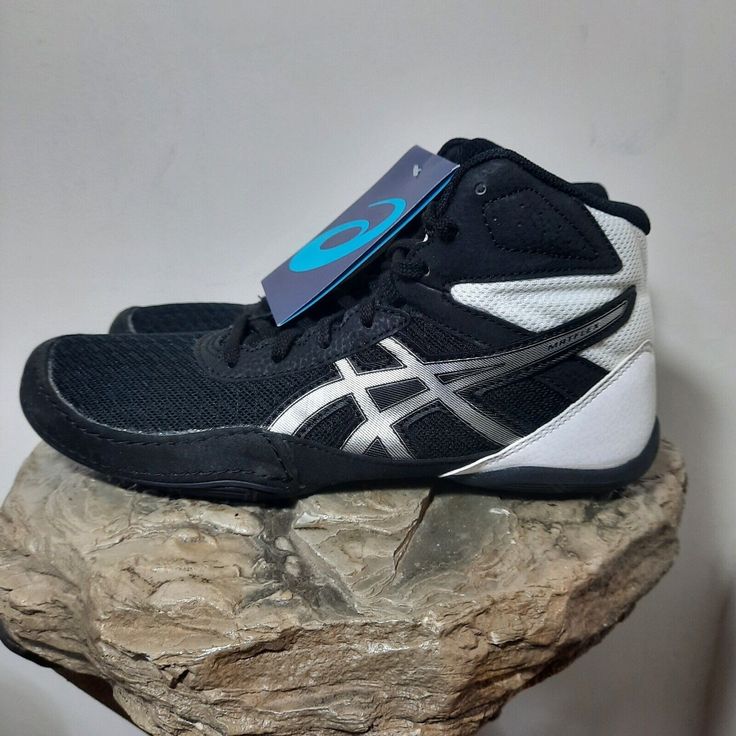 a pair of black and white shoes sitting on top of a rock next to a blue tag