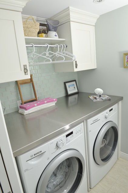 a washer and dryer in a small room with white cupboards on the wall