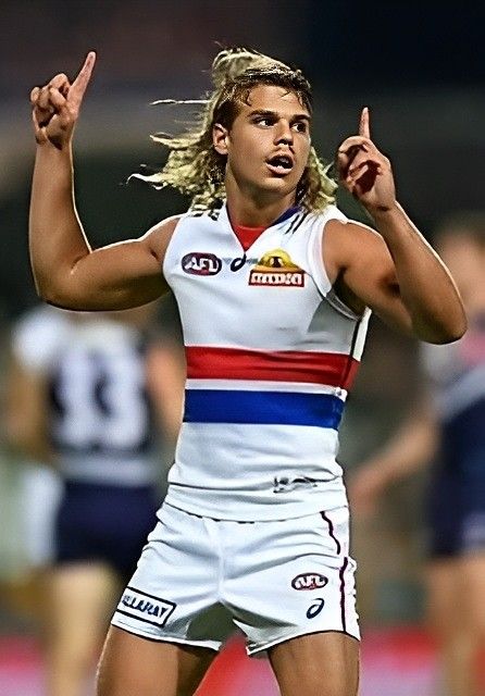 a male afl player is holding his hand up in the air and pointing at something